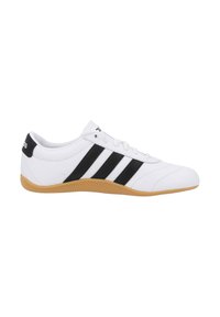 Vit atletisk sko i syntetmaterial, med tre svarta ränder och gummisula. Rundad tå och snörningsdesign.