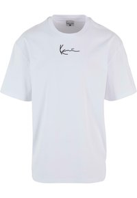 T-shirt blanc en coton avec un logo noir brodé sur la poitrine. Il a un col rond et des manches courtes, avec une coupe décontractée.