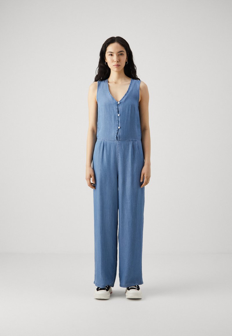 Šampanj jumpsuit z V-izrezom, sprednjim gumbom, brez rokavov, širokimi hlačnicami in sproščenim krojem, v svetlo modri barvi.