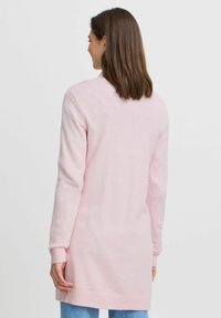Cardigan lungo e morbido di colore rosa, realizzato in tessuto a maglia, con polsini e orlo a costine, dalla linea dritta e design minimalista.
