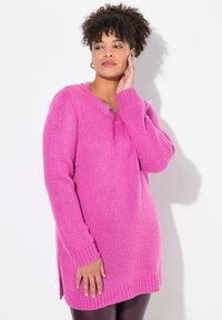 Pull en maille rose surdimensionné avec des manches longues, décolleté en V, bords côtelés et fentes latérales. Texture douce avec un design ample et décontracté.