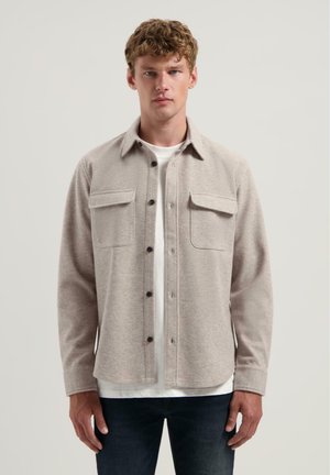 Beige wolmix overhemdjacket met twee borstzakken, knoopsluiting en een kraag. Zachte textuur en een iets relaxte pasvorm.