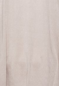 Světlé béžové látky s měkkou, hladkou texturou, vykazující jemný lesk a mírně pomačkaný vzhled. Žádné viditelné vzory ani detaily.