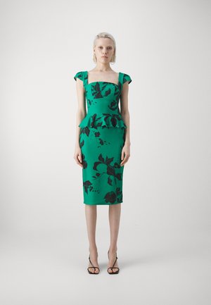 Robe ajustée verte avec une taille peplum, des manches courtes en forme de cap, et des motifs de feuilles noires. Tissu lisse, longueur midi et décolleté carré.
