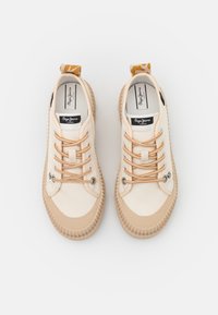 Baskets en toile beige avec semelles en caoutchouc texturées, lacets orange à motifs, languettes de traction et étiquettes "Pepe Jeans London" à l'intérieur.