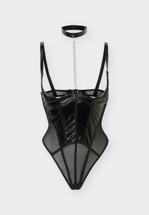Corset noir transparent et brillant avec bretelles réglables, accompagné d'un collier assorti relié par une chaîne en or sur un fond uni.