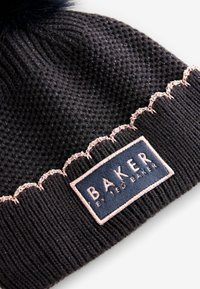 Berretto in maglia nera con un motivo testurizzato, caratterizzato da un accento a scallop rosa e un'etichetta di stoffa rettangolare con la scritta "BAKER" in caratteri in grassetto.