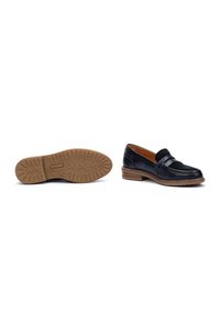 Mocasines de cuero negro con tacón plano, con una correa decorativa. La suela es de goma con un dibujo para mayor agarre.