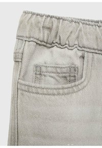 Vaaleanharmaat joustavat vyötäröhousut, joilla on pieni etutasku näkyvissä, tarkkailemassa yksityiskohtaista ompelua ja kankaan tekstuuria.