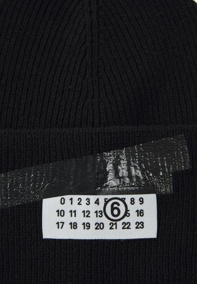 Căciulă tricotată neagră cu textură ribbed. Are un etichetă albă cu numerele 0-23, parțial acoperită de o bandă transparentă. Design simplu și functional.