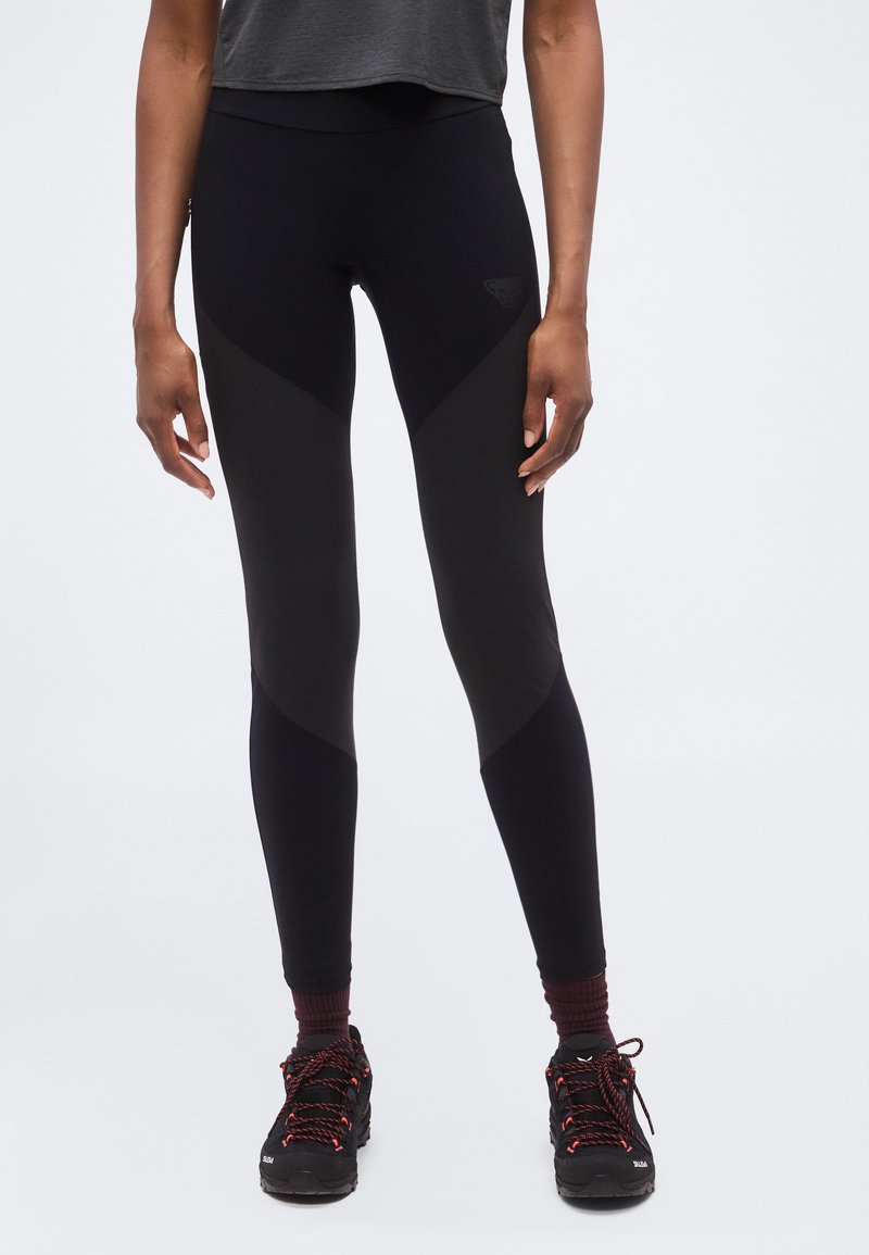 Πόδια με μαύρα leggings ψηλής μέσης με διάφανα πάνελ, συνδυασμένα με μπουρντό κάλτσες και μαύρα πεζοπορικά παπούτσια με κόκκινα κορδόνια.