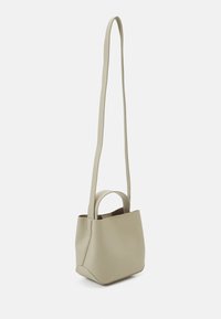 Piccola borsa in pelle beige con un design minimalista, dotata di una tracolla lunga e di un manico corto per opzioni di trasporto versatili.