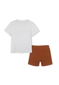 Completo a due pezzi composto da una camicia bianca in cotone a maniche corte e pantaloni corti marroni. La camicia presenta un classico collo rotondo; i pantaloni corti sono aderenti.