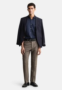 Tumesinine pintsak, teksapluus nööpidega, pruun hundhammasmustriga püksid, must vöö ja mustad kleitkingad. Lihtne ja kohandatud stiil.