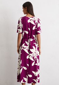 Lila Midikleid mit kurzen Ärmeln, ausgestattet mit weißen Blumenmuster, Kordelzug in der Taille und fließendem Stoff. 