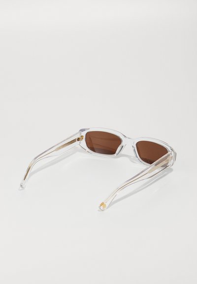 Clear-frame sunglasses with brown lenses. Features sleek, angular design and gold accents on the temple arms. Smooth texture throughout.