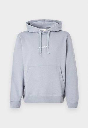 Gaiši pelēks džemperis ar kapuci, izgatavots no mīksta auduma, ar priekšējo kabatu, kapuces auklu un ribveida aprocēm un apakšu. Uz krūts ir izteikts neliels logo.