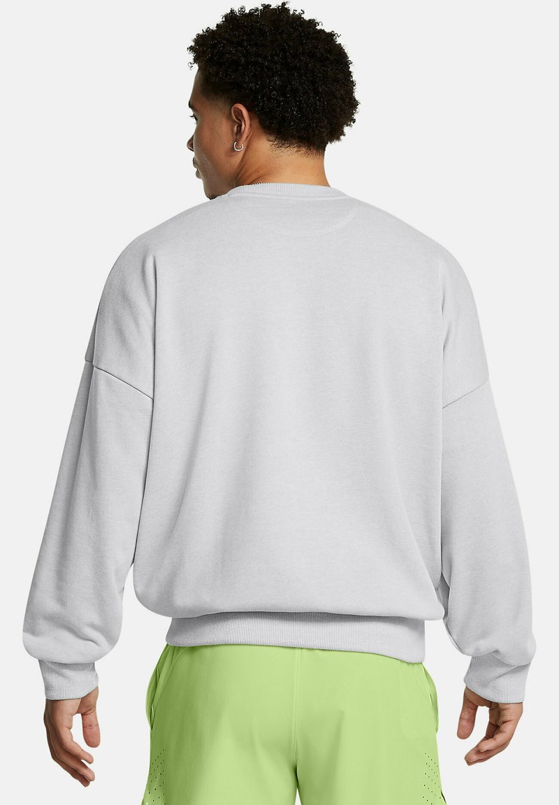 Hombre de espaldas vistiendo un sudadera de manga larga gris claro y pantalones cortos verde lima con detalles perforados.