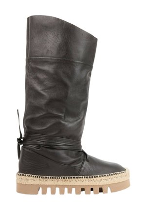 Botte haute en cuir noir avec sangle enveloppante, semelle beige cousue style espadrille et semelle extérieure en caoutchouc épaisse.