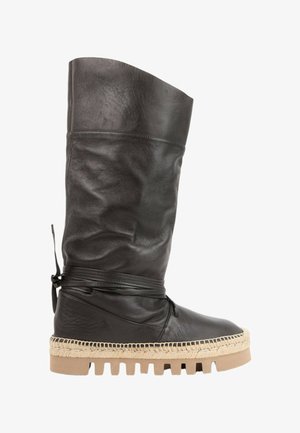 Botte haute en cuir noir avec sangle enveloppante, semelle beige cousue style espadrille et semelle extérieure en caoutchouc épaisse.