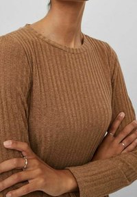 Maglione a coste marrone con scollatura rotonda e maniche lunghe, caratterizzato da un tessuto testurizzato e una silhouette aderente.