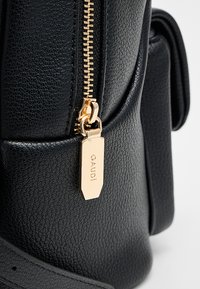 Borsa a mano in pelle nera texturizzata con cerniera dorata e targhetta con incisione "GAUDI". Caratterizzata da un design a soffietto e tracolla.