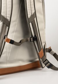 Gray fabric backpack featuring a tan leather accent, adjustable straps, and sturdy hardware. Interior shows padded compartment and seams.