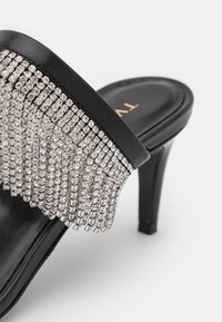 Svart klacksandaler med en bred ovandel prydd med kaskad av rhinestones, slät lädertextur och en elegant, spetsig tå.