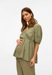 Maglietta premaman verde oliva con scollatura a V, vita arricciata e maniche corte a sbuffo, realizzata in tessuto leggero e texturizzato.
