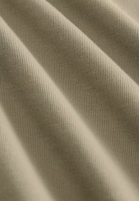 Beiger Stoff mit einem feinen, strukturierten Gewebe; weist subtile horizontale Linien und eine glatte Oberfläche auf, die sich in sanften Falten drapiert.