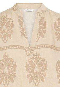 Haut en tissu beige avec des motifs damassés floraux brun clair, un décolleté en V et un petit col montant.