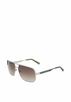 Occhiali da sole con montatura in metallo argentato, lenti rettangolari sfumate marroni e logo "GUESS" sulle aste con punte nere.