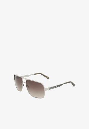 Occhiali da sole con montatura in metallo argentato, lenti rettangolari sfumate marroni e logo "GUESS" sulle aste con punte nere.