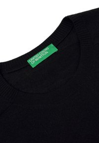 Černý pletený svetr s kulatým výstřihem. Zelená nášivka nese nápis "UNITED COLORS OF BENETTON." Čistý design, jemná textura, minimální detaily.