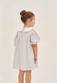 Grau kariertes Kleid mit kurzen Puffärmeln, weißem Spitzensaum und Knopfverschluss hinten. Weicher Stoff mit lockerer Passform. Geeignet für Kinder.