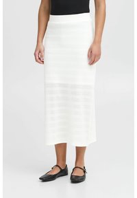 Witte gebreide midi-skirt met een textuur van strepen, een aansluitende tailleband en een rechte silhouet. Gecombineerd met zwarte platte schoenen.