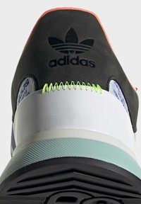 Tenisky Adidas, černý textilní svršek, bílá mezipodešev, zelené švy, růžové akcenty, texturovaná máta na podrážce, s logem na patě a vzorovými detaily.
