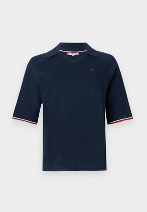 Polo de punto azul marino con cuello en V y mangas cortas; detalles a rayas en blanco y rojo en los puños; pequeño logo en el pecho.