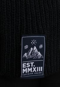 Black knitted beanie with a textured pattern, featuring a rectangular fabric label displaying mountain graphics and "EST. MMXIII" in white.