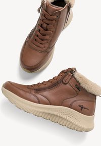 Hnědé kožené vysoké tenisky s texturovaným povrchem, měkkou kožešinovou podšívkou, šněrováním vpředu a bočním zipem, s béžovou gumovou podrážkou.