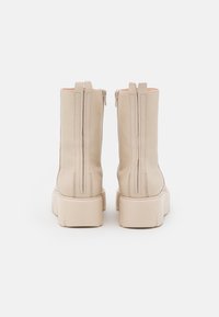 Beige leather ankle boots with a smooth texture, two back zippers, and thick platform soles. Stitched detailing along the seams.