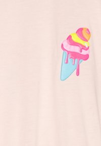 T-shirt rose clair avec un graphique de cône de glace coloré et texturé, comportant des détails rose, jaune et bleu, rehaussé par des effets de glaçage.