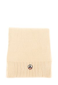 Écharpe en tricot beige avec texture côtelée, présentant un patch de logo circulaire avec des accents bleus et rouges en bas. Forme rectangulaire.