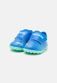 Blue athletic shoes with a smooth, shiny surface, dotted with white patterns. Velcro straps on top, green rubber soles with spikes.