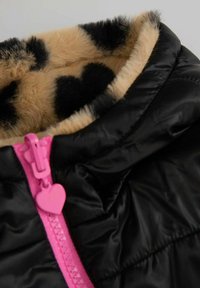 Kurtka puchowa o błyszczącej czarnej powierzchni, różowym suwaku z zawleczką w kształcie serca oraz beżowym futerkiem z czarnymi plamkami.
