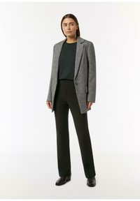 Szary teksturowany blazer z klapami, czarny sweter z dzianiny, czarne spodnie i czarne botki za kostkę, stojąc na białym tle.