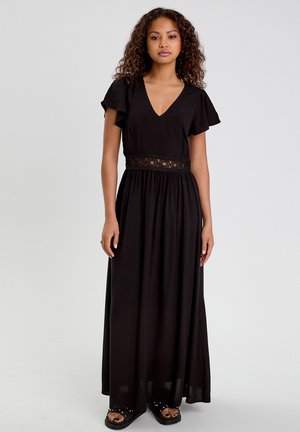 Vestido maxi negro con mangas cortas tipo alita, escote en V y detalle de encaje en la cintura. Tejido suave y silueta fluida.