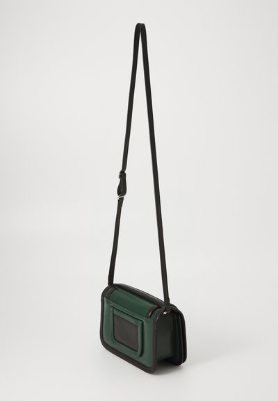 Sac bandoulière en cuir vert avec des accents noirs, de forme rectangulaire, poche avant et bandoulière réglable. Texture lisse avec des détails contrastants.