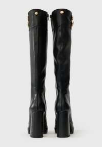 Par črne visoke usnjene škornje do kolen z blokastimi petami in zlatimi gumbi blizu vrha.