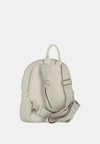 Zaino in pelle beige con doppie maniglie corte e una tracolla regolabile. Presenta un compartimento principale con zip e cinturini con logo in rilievo.